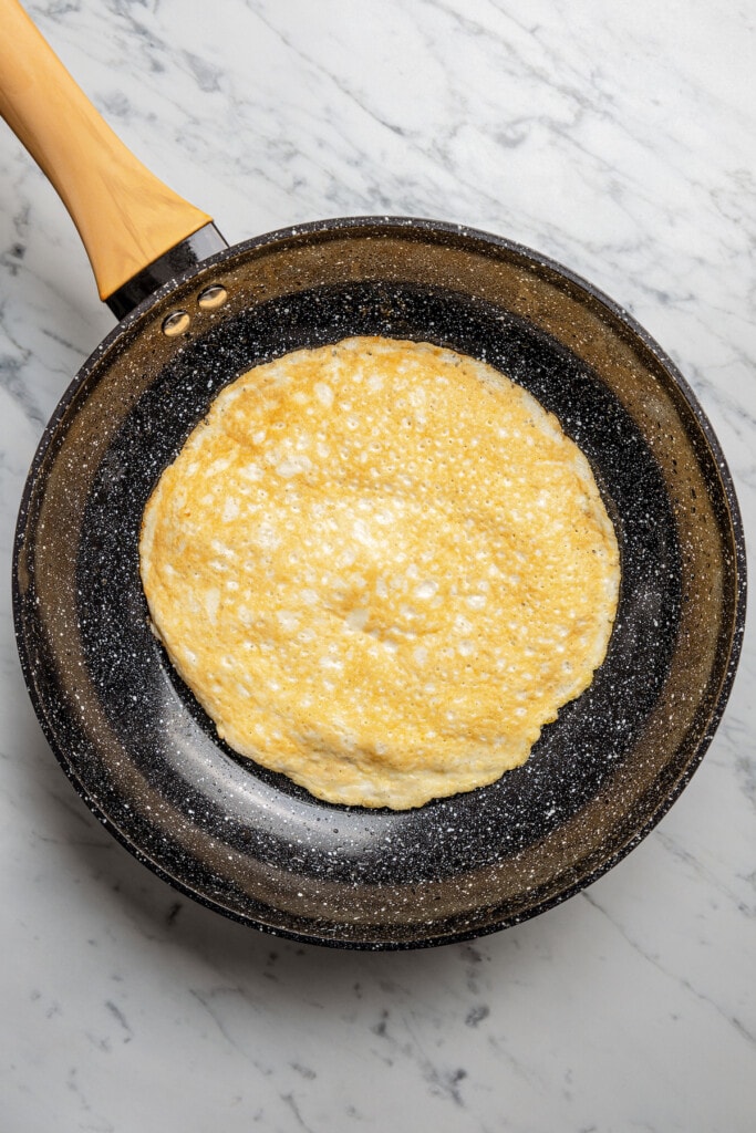 Flipping an egg white wrap in a skillet.