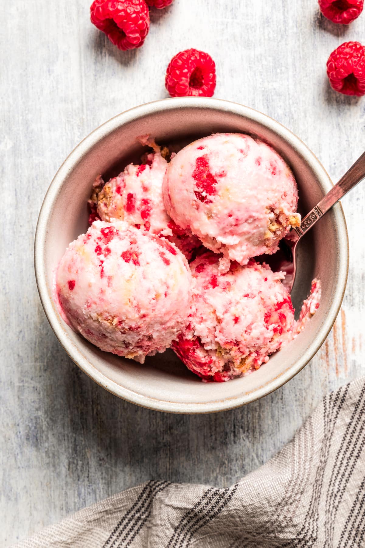Overhead image of raspberry cottage cheese ice cream served in a bowl with a spoon.