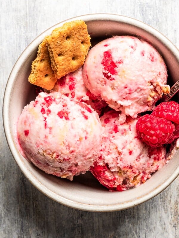 Overhead image of raspberry cottage cheese ice cream served in a bowl and garnished with fresh raspberries and graham crackers.