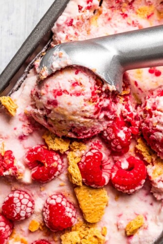 Taking a scoop of raspberry cottage cheese ice cream out of a loaf pan.