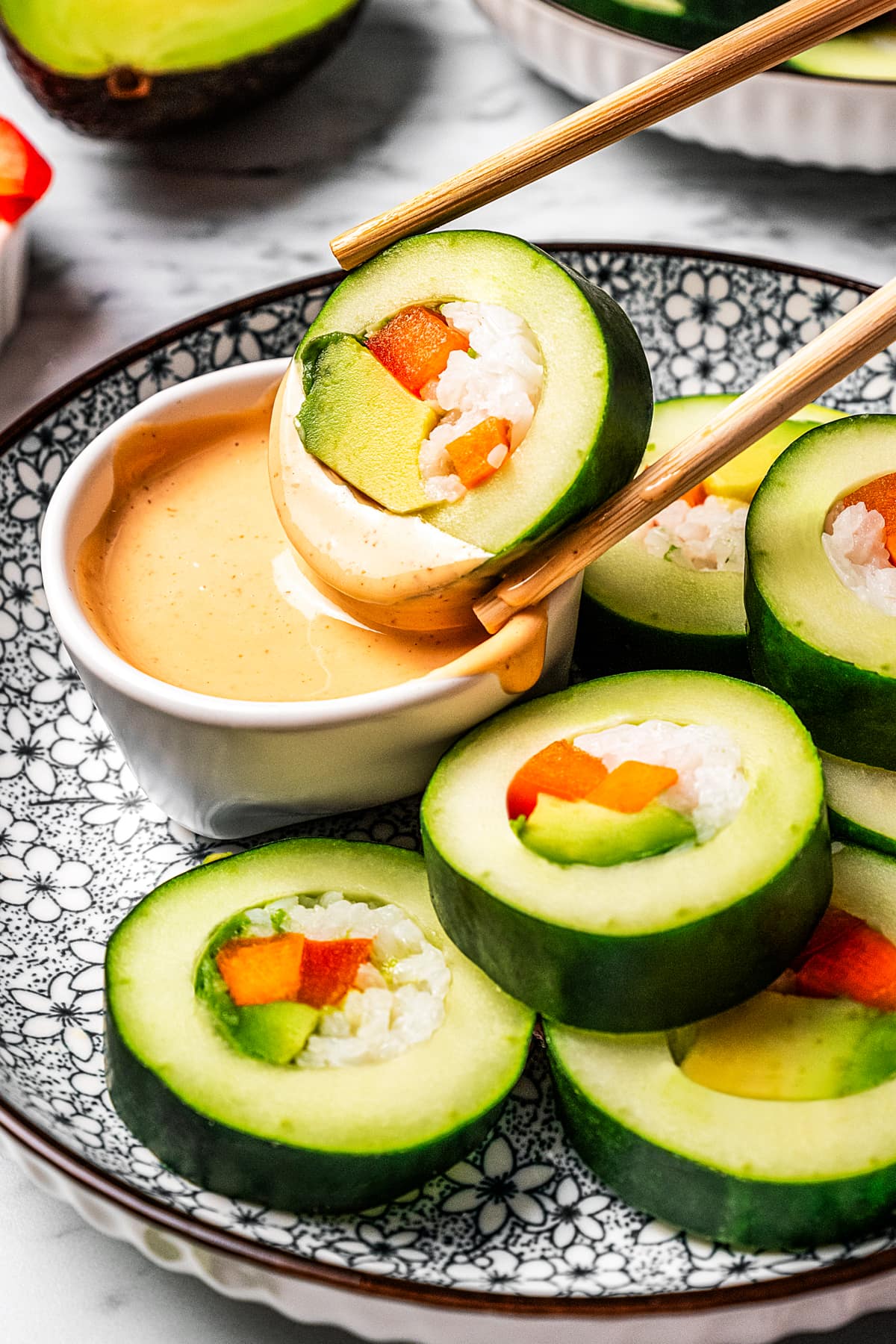 Dipping a slice of a cucumber roll in sriracha aioli.