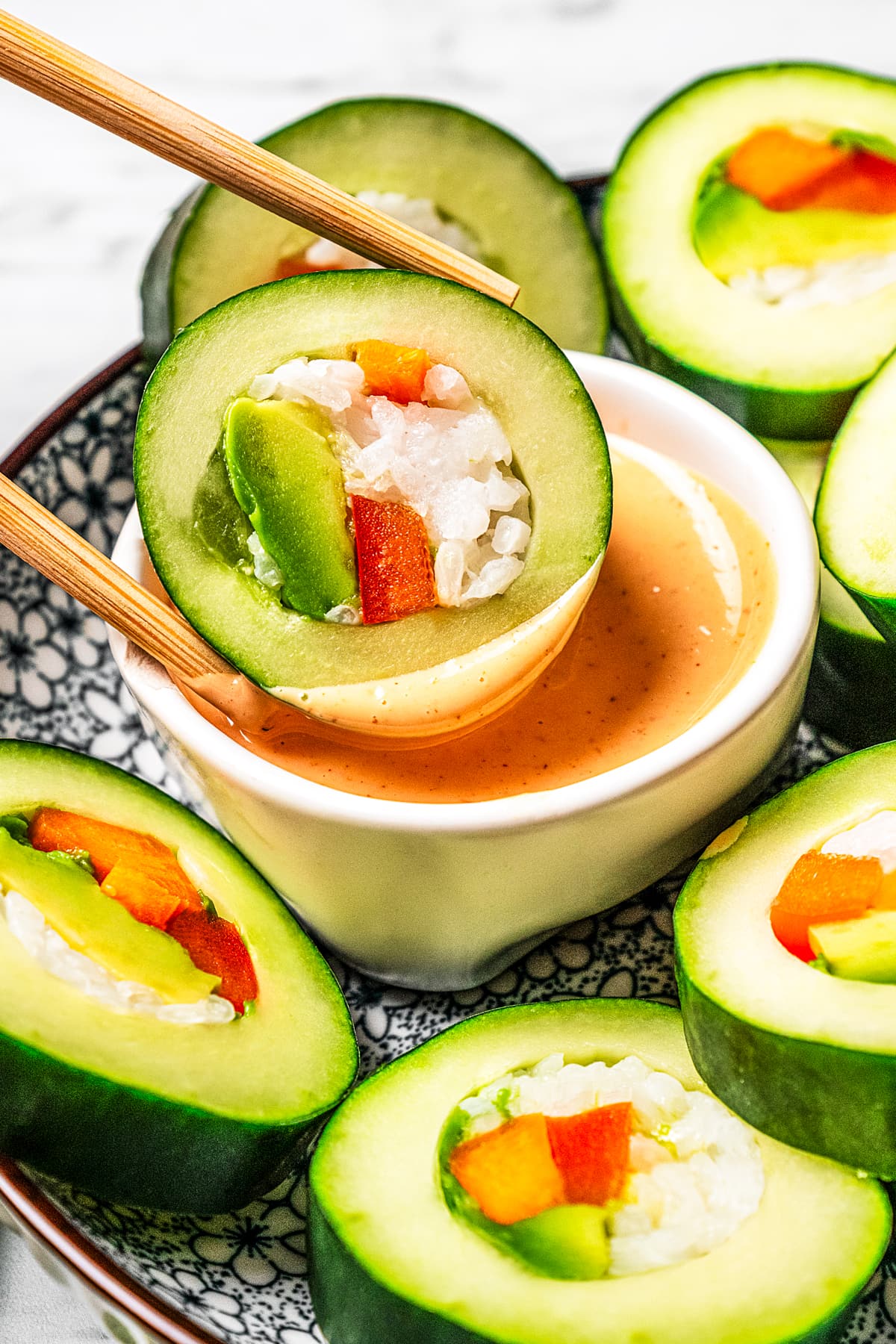 Dipping a slice of a cucumber roll in sriracha aioli.