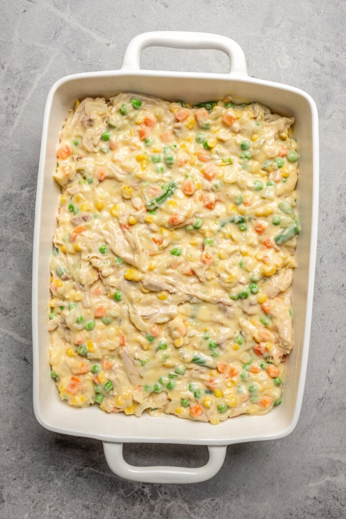 Creamy chicken and veggie filling in a casserole dish ready to be topped with stuffing.
