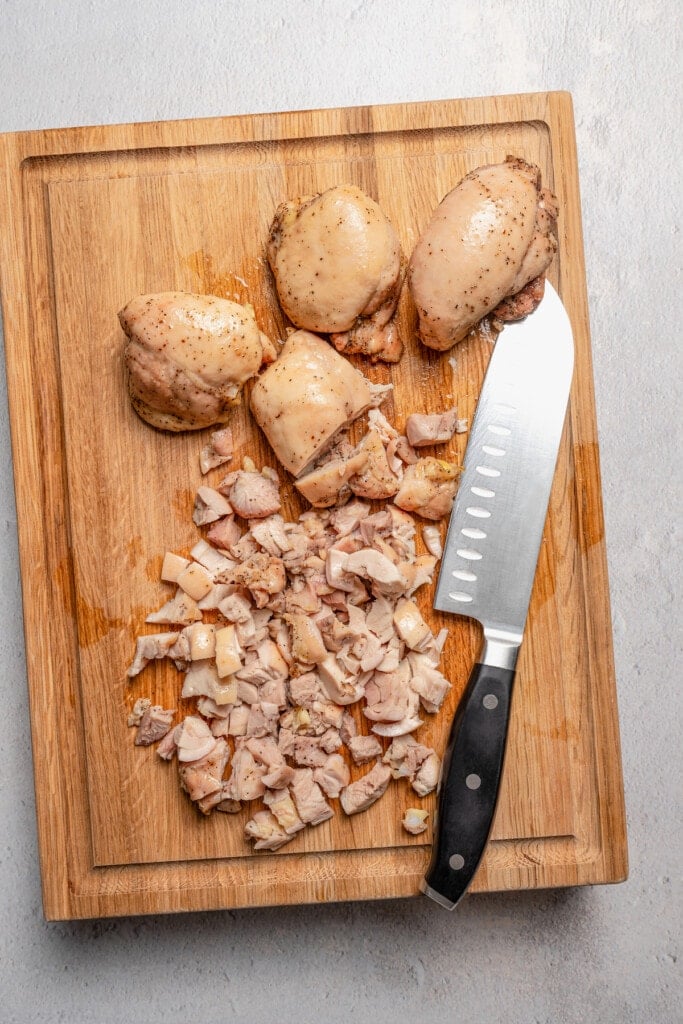 Chopping roasted chicken on a cutting board.