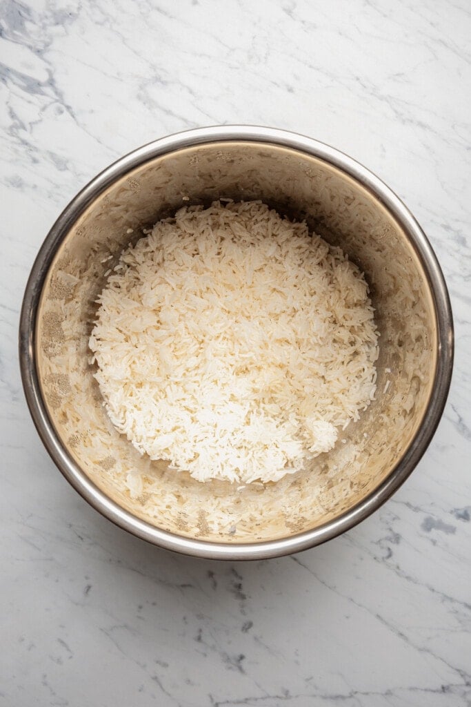 Cooked white rice in the basin of a pressure cooker.