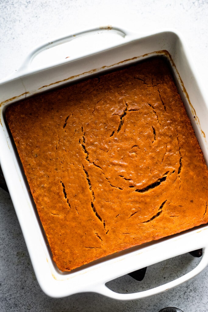 Baked pumpkin bars in a white square baking dish.