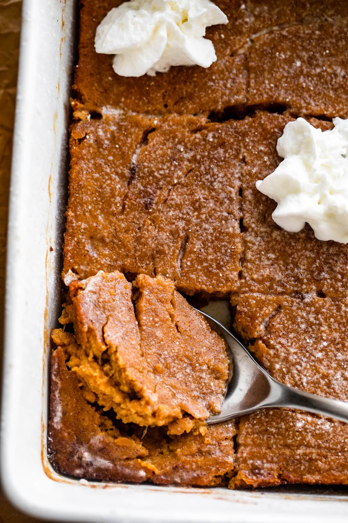 Spooning out Pumpkin Bars with a spoon from a baking dish.