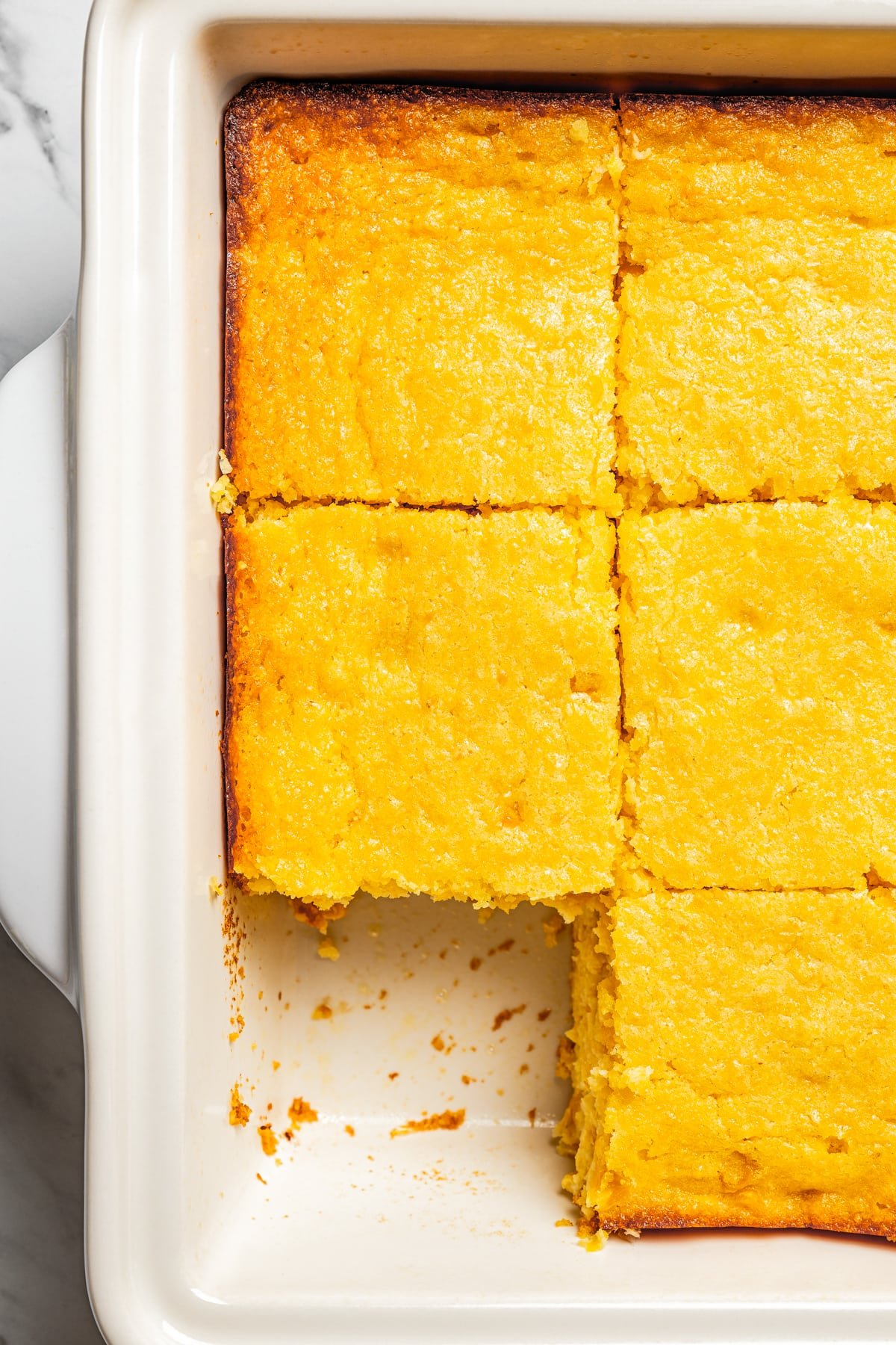 Closeup image of sliced cornbread casserole in a baking pan.