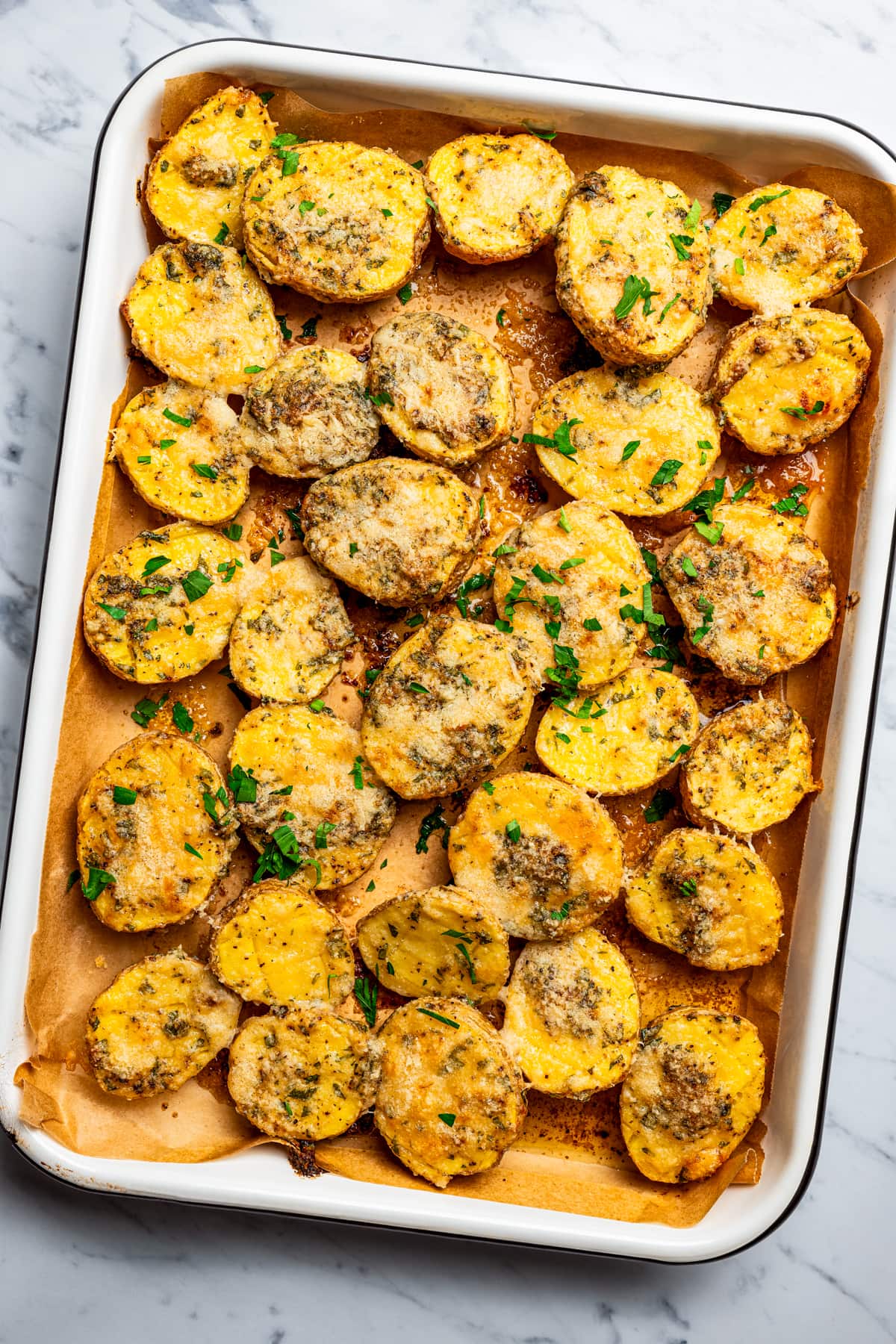 Overhead image of parmesan crusted potatoes arranged on a baking sheet.