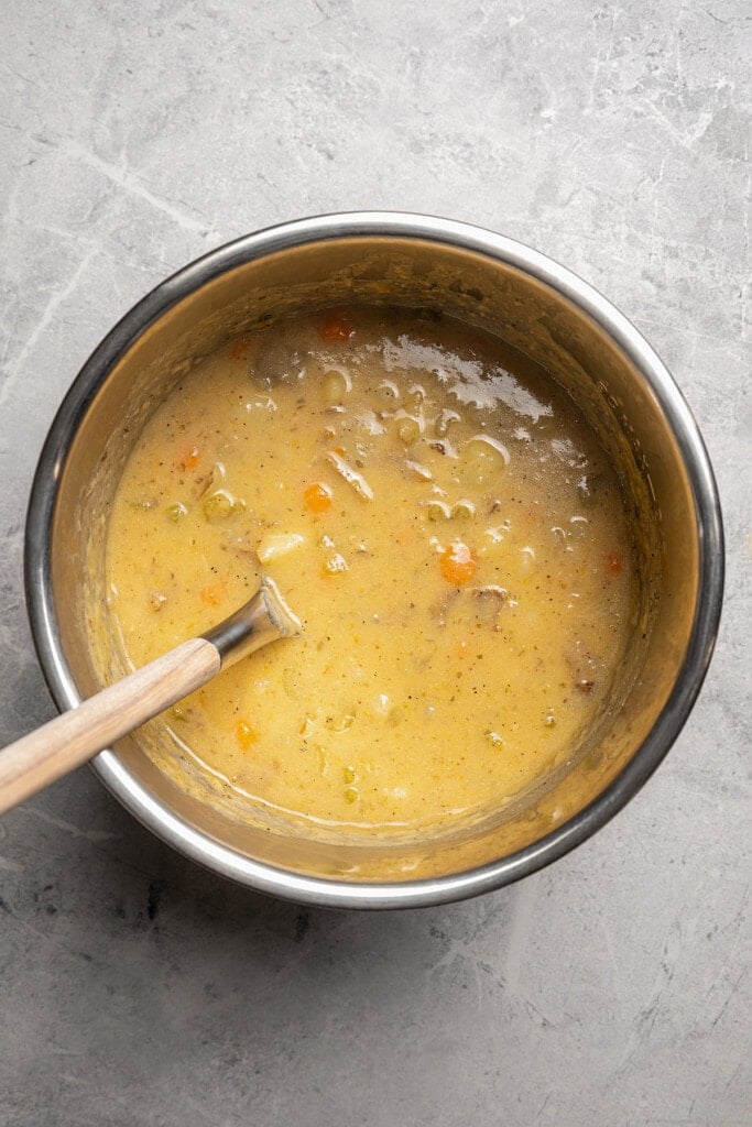 Stirring a cornstarch slurry into Instant Pot potato soup to thicken it.