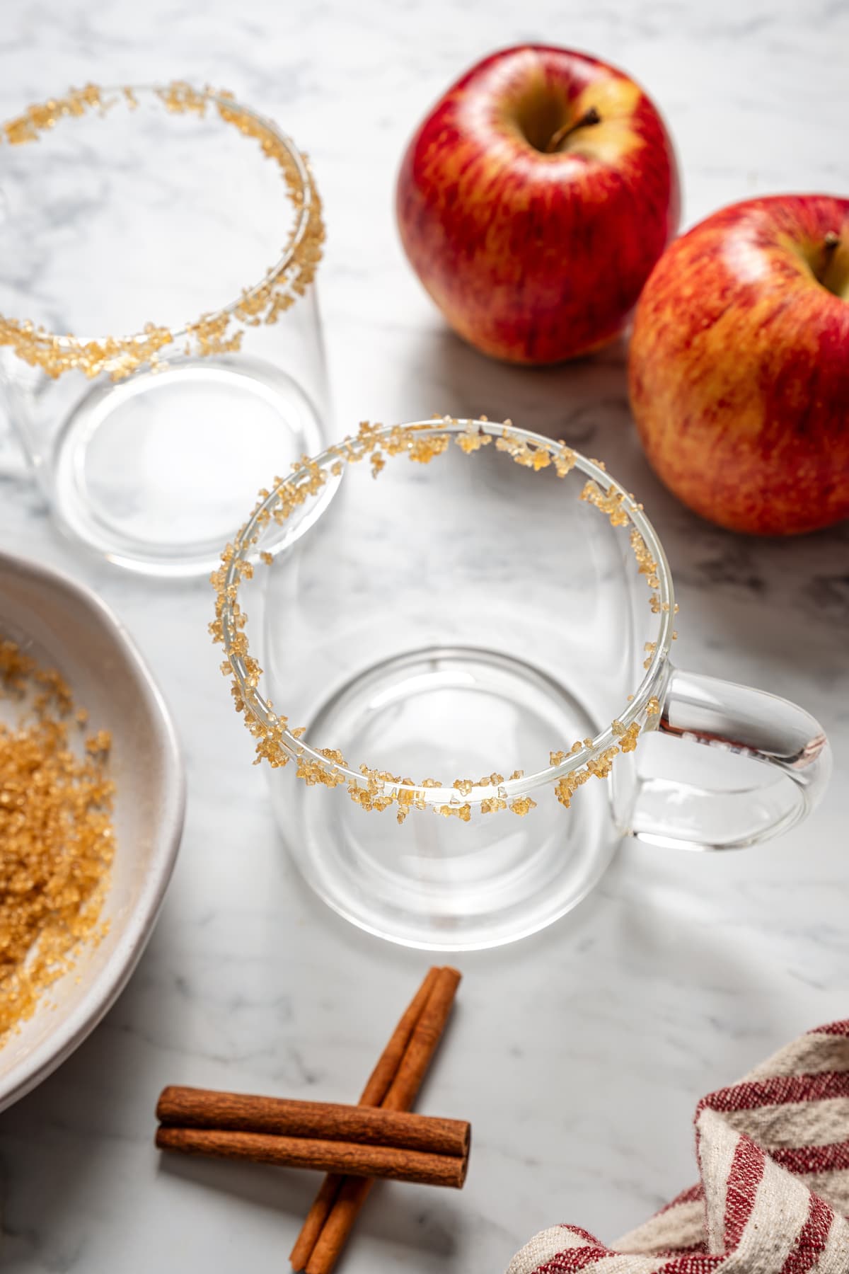 Adding brown sugar to the rim of 2 glass mugs.