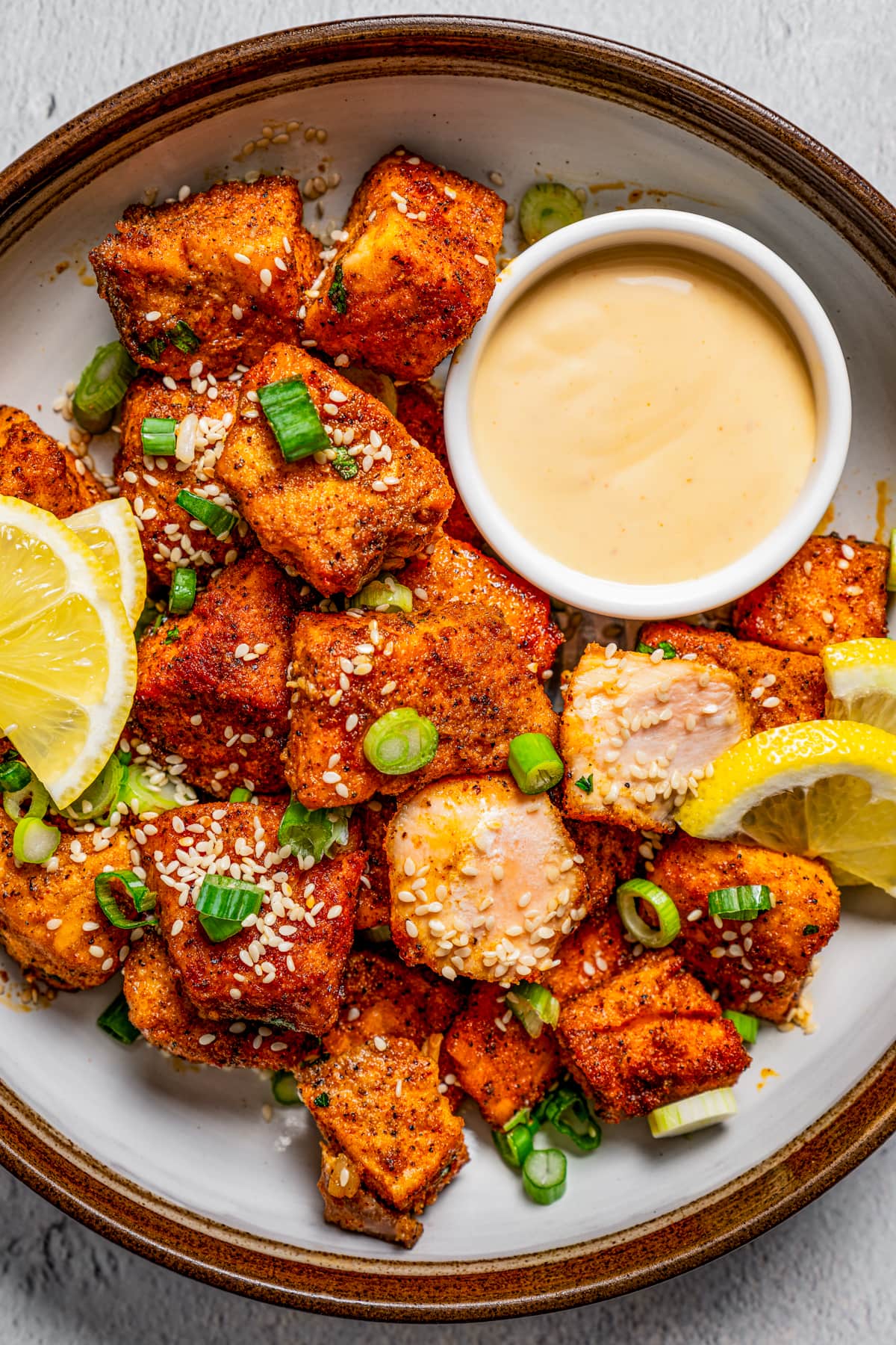 A plate of air fryer salmon bites with a bowl of dipping sauce.