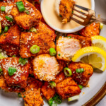 Dipping salmon bite into sauce.