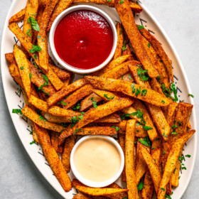 Overhead image of Cajun fries on a serving platter with ketchup and aioli.