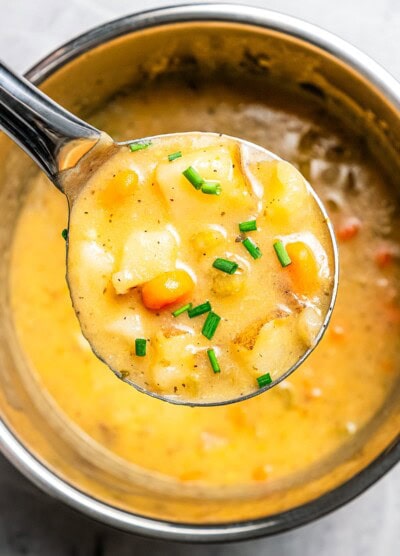 Holding a ladle full of Instant Pot potato soup up to the camera.