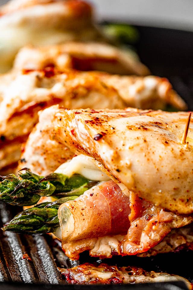 Close-up image of cooked chicken breasts rolled around asparagus spears and prosciutto.