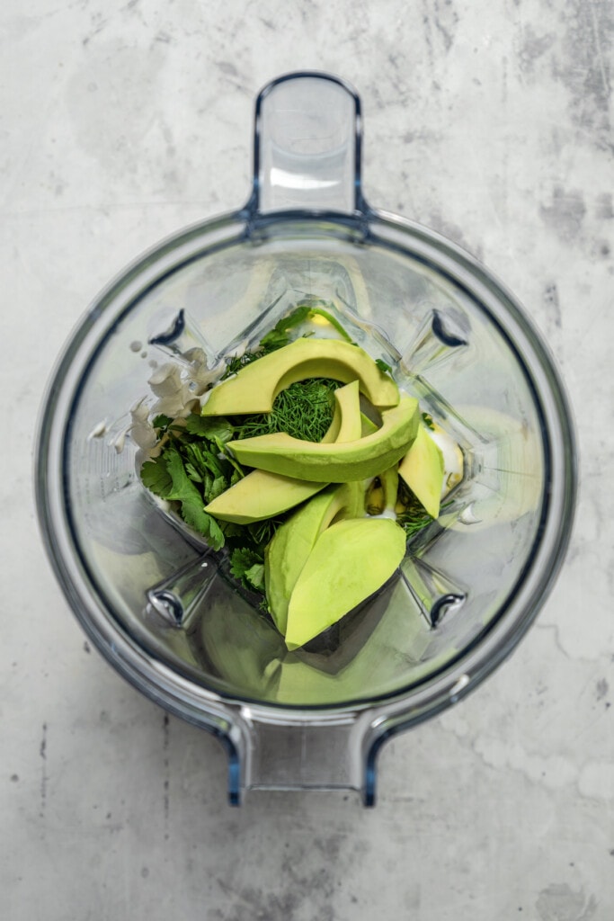 Adding ingredients for avocado lime ranch dressing to a blender.