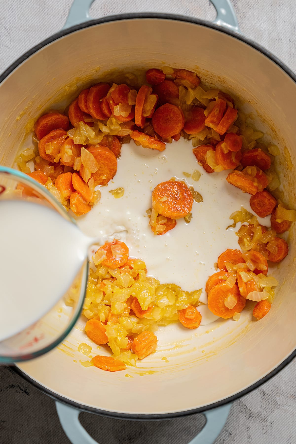 Rich, creamy, and loaded with broccoli cheddar flavor, broccoli cheese soup is a great way to sneak extra veggies into your weekly routine. Pouring milk into a soup pot with sauteed veggies and roux.
