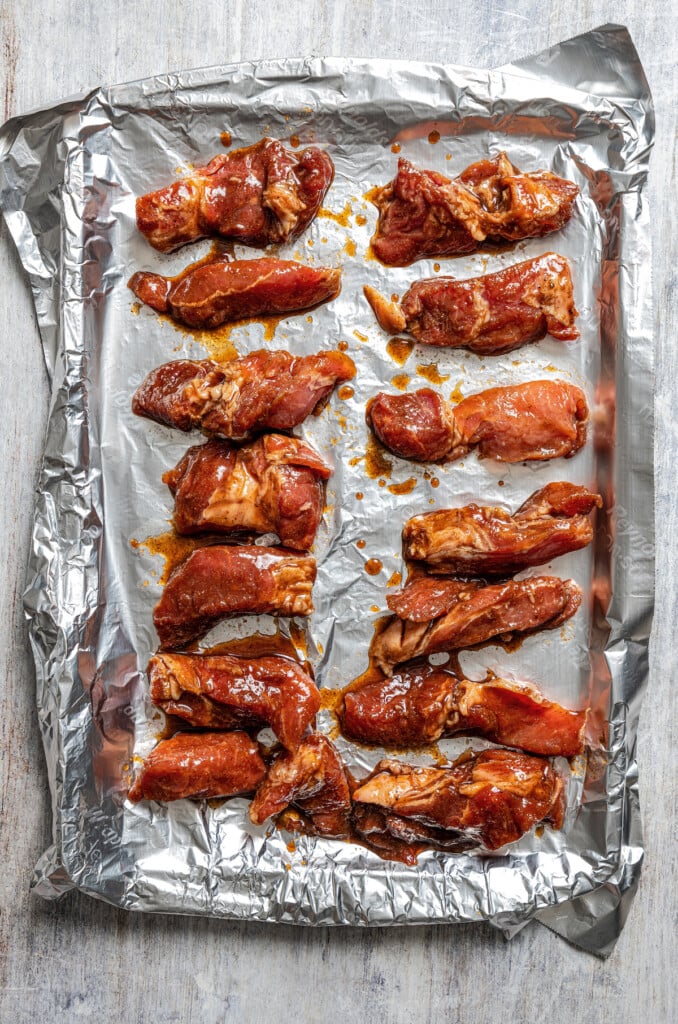 Marinaded Chinese boneless spare ribs on a baking sheet lined with aluminum foil, ready to bake.