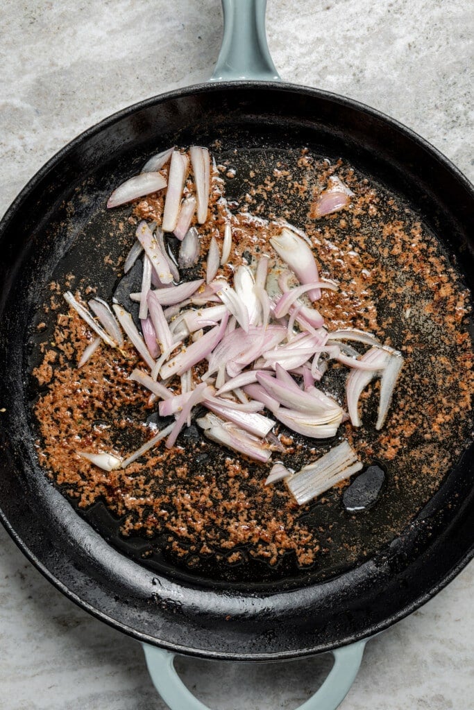 Adding sliced shallots to a skillet with melted butter.