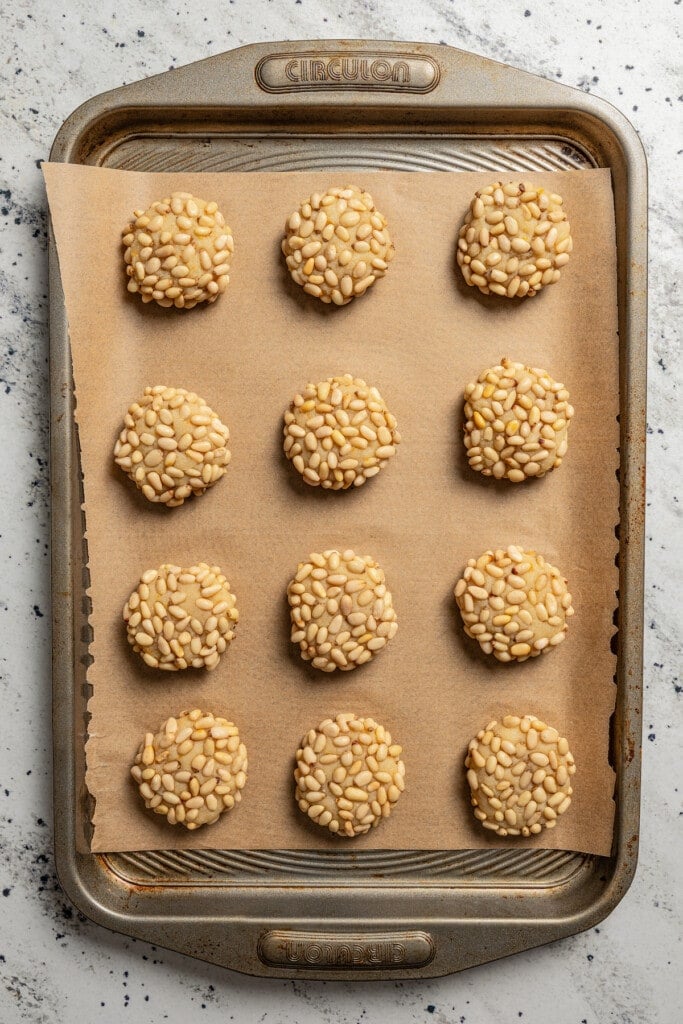 Pignoli cookies ready to bake on a baking sheet lined with parchment paper.