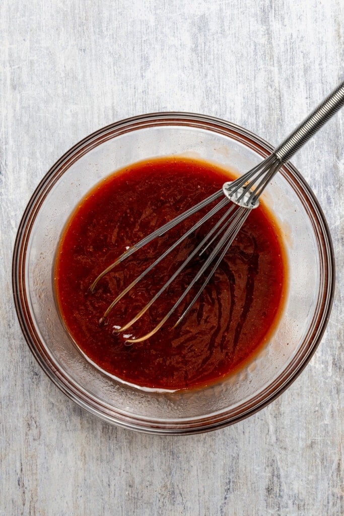 Whisking together coca-cola and BBQ sauce.