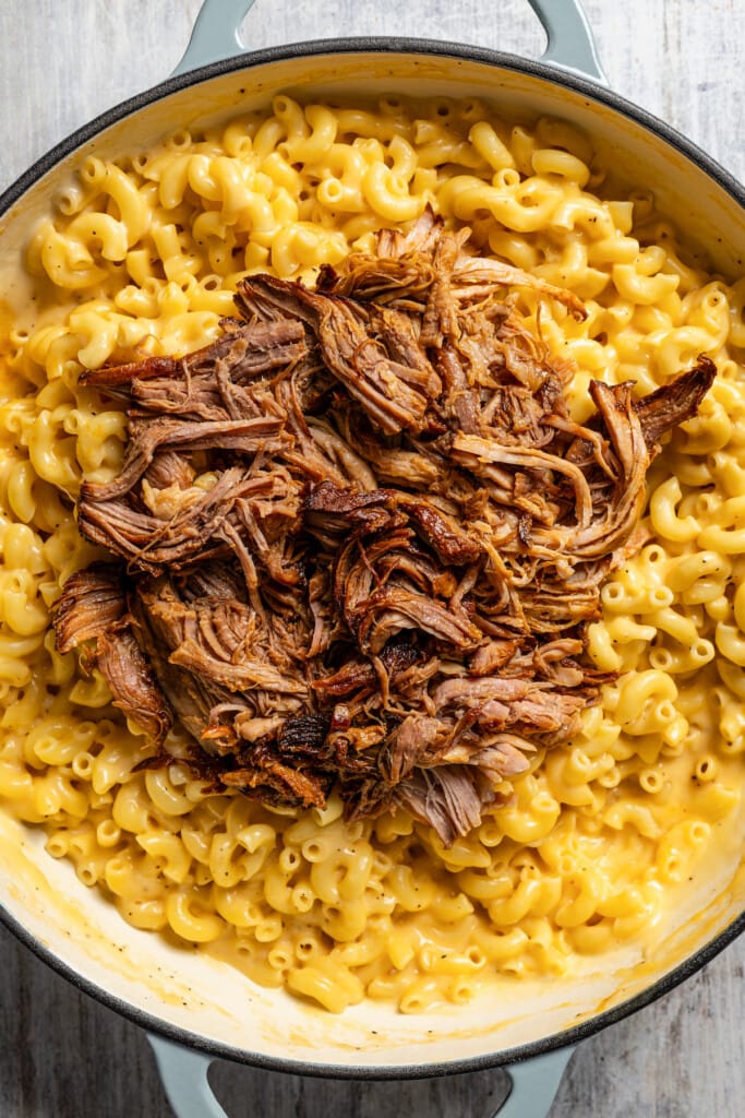 Adding pulled pork to mac and cheese.