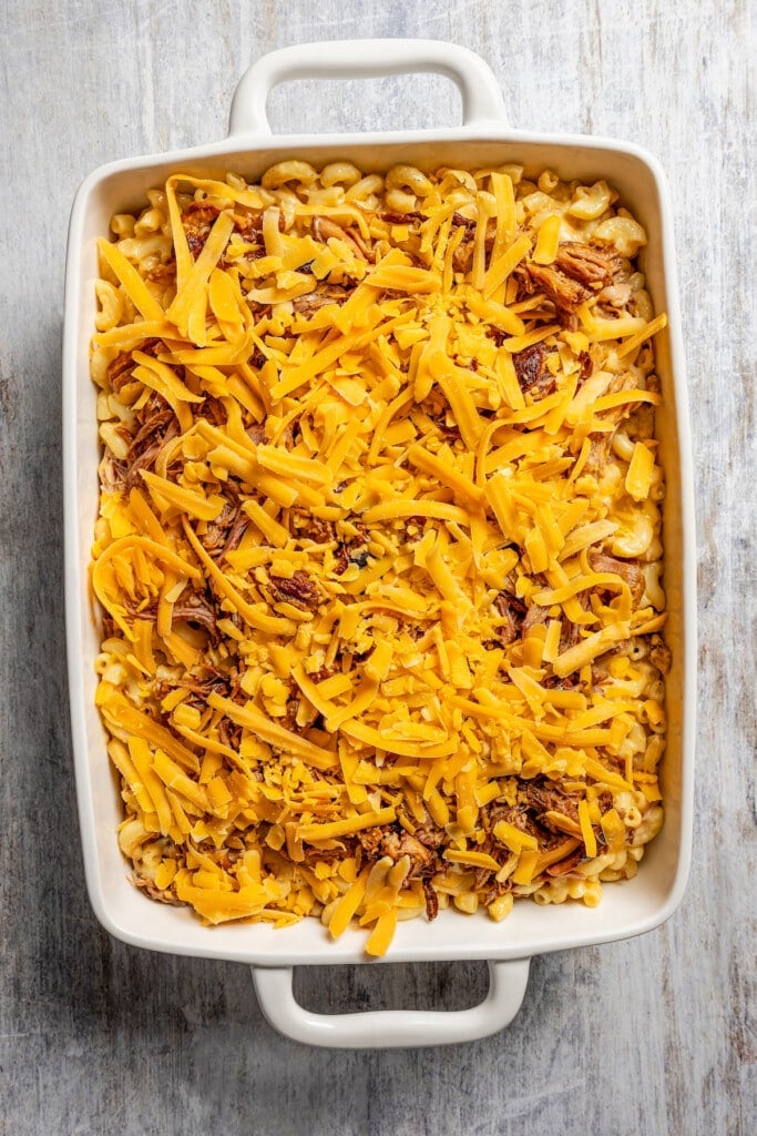 Scattering extra pulled pork and cheddar cheese of pulled pork mac and cheese.