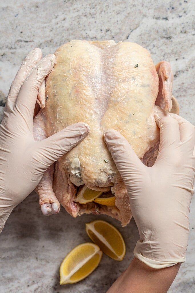 Rubbing cream cheese and herbs under the skin of a chicken.