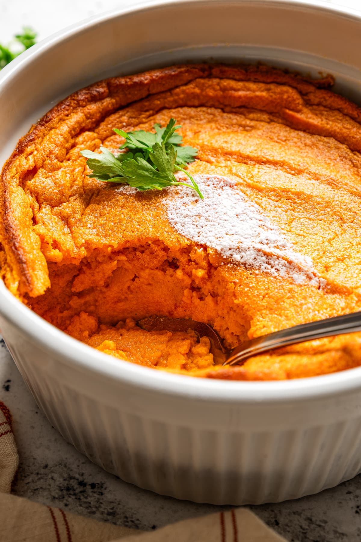 Carrot souffle in a baking dish with a spoon in it.