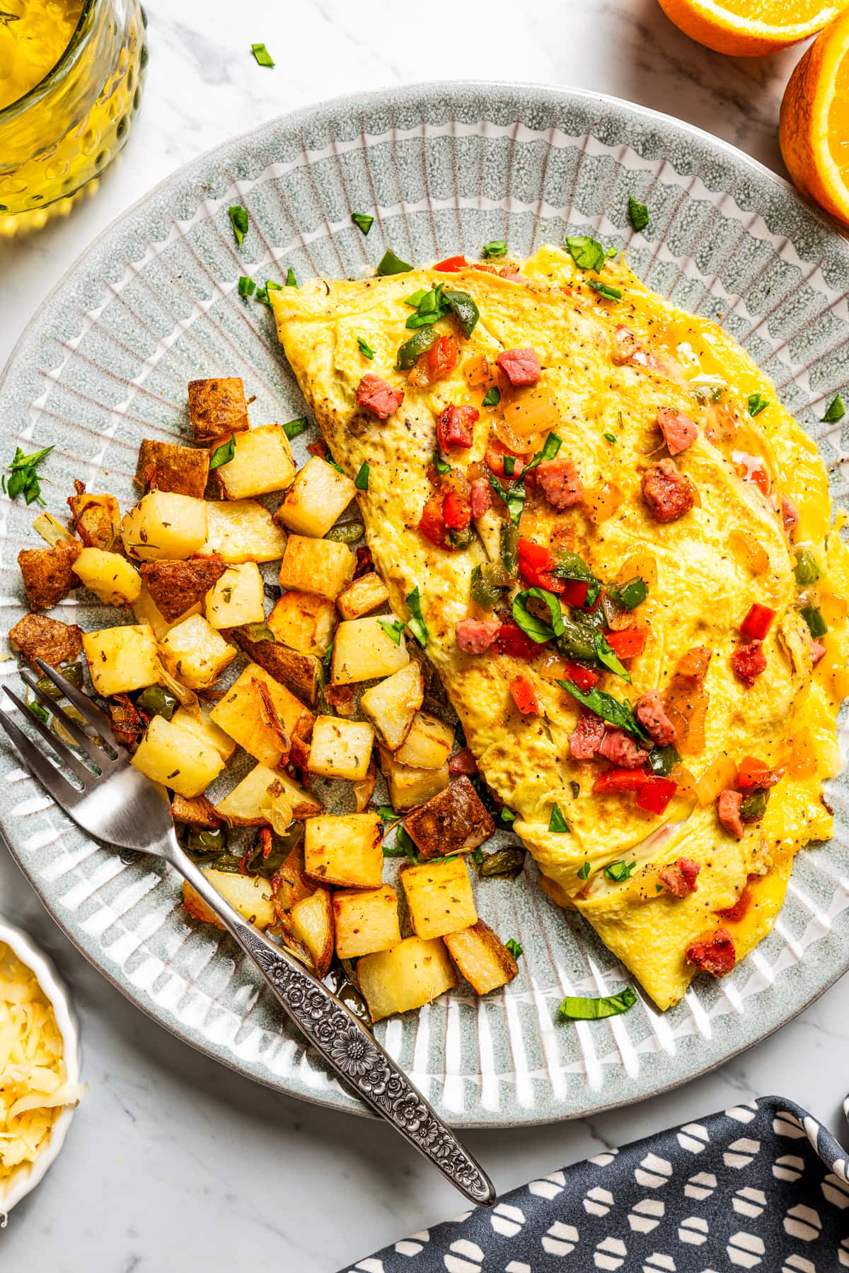 Overhead image of a Western omelette served on a plate with diced breakfast potatoes.