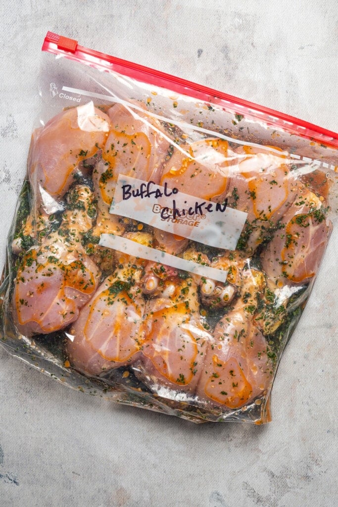Chicken drumsticks in buffalo marinade in a ziplock bag.