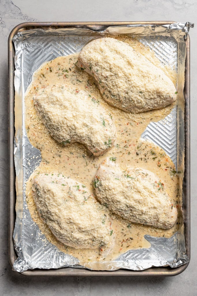 Sprinkling Italian dressing chicken with grated parmesan.