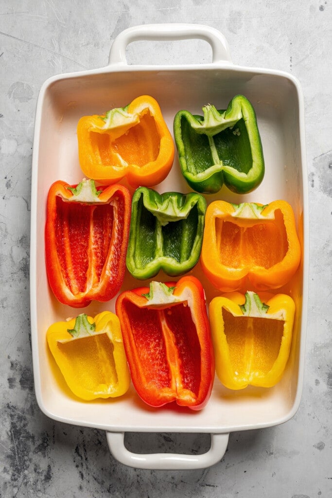Arranging halved bell peppers in a baking dish.