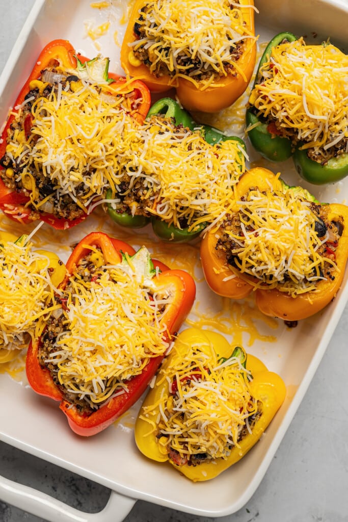 Topping quinoa stuffed peppers with cheese.