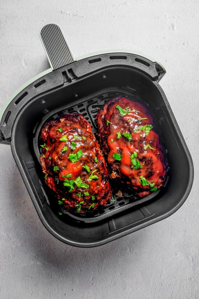 Overhead image of two glazed air fryer meat loaves inside the basket of an air fryer.