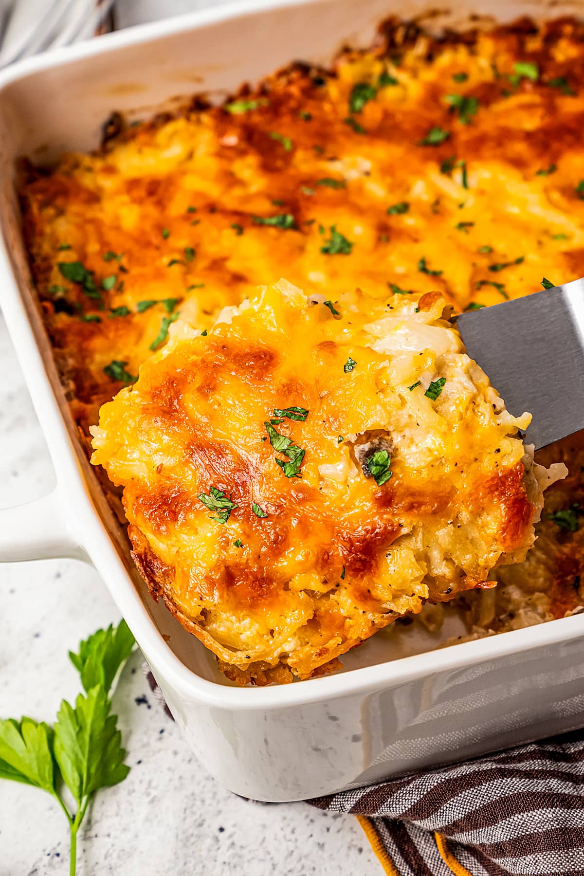 A spatula taking a slice out of cheesy hashbrown casserole.