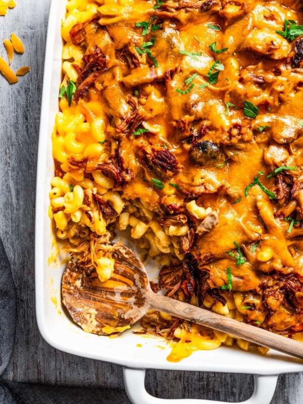 Pulled pork arranged atop mac and cheese in a baking dish.