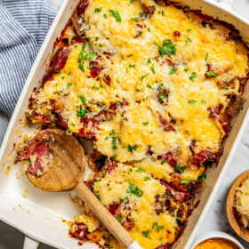 Overhead image of a Reuben casserole in a baking dish, with a wooden spoon resting inside the dish.