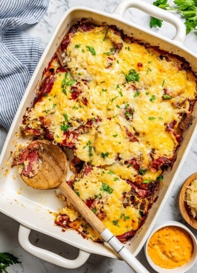 Overhead image of a Reuben casserole in a baking dish, with a wooden spoon resting inside the dish.