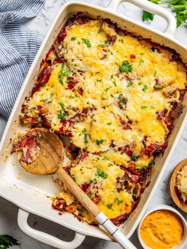 Overhead image of a Reuben casserole in a baking dish, with a wooden spoon resting inside the dish.