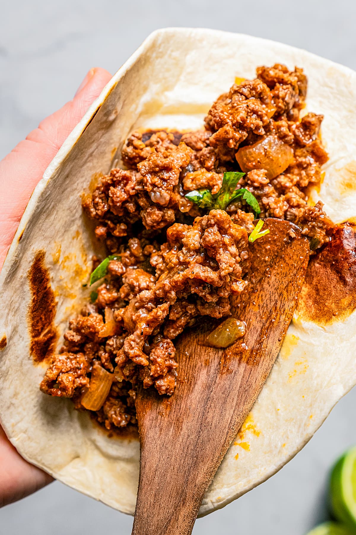 Stuffing a flour tortilla with taco meat.
