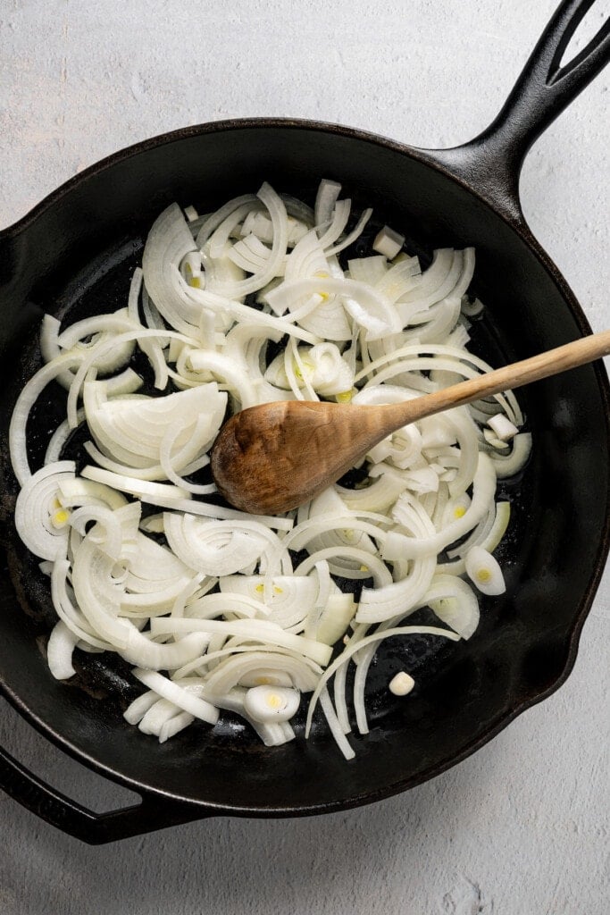 Adding onions to a skillet to caramelize.