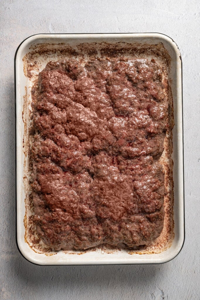 A sheet of seasoned, cooked ground beef in a baking pan.