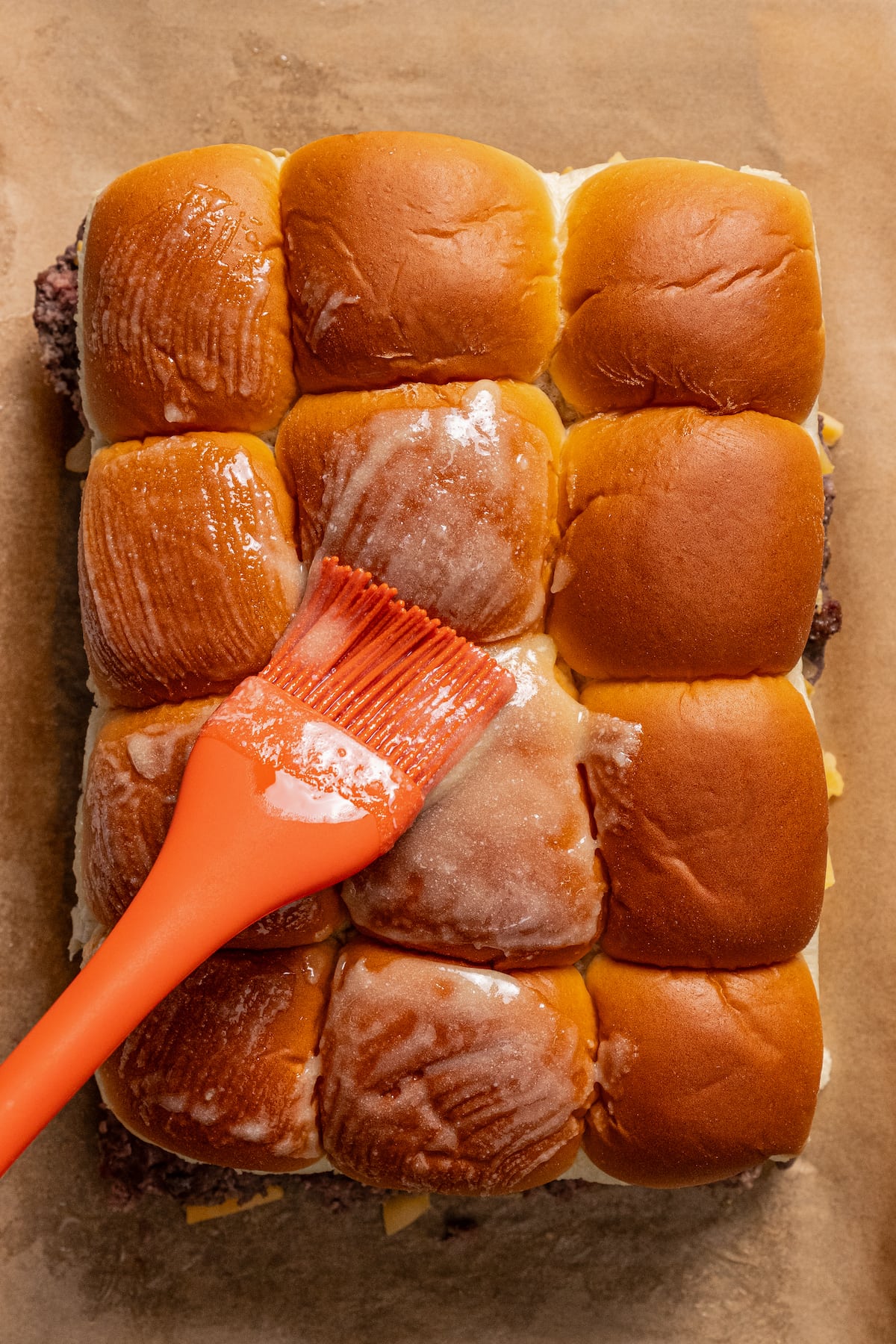 Brushing cheeseburger sliders with melted butter.