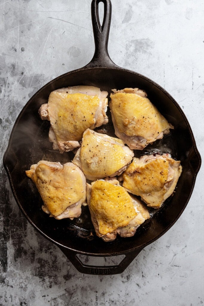 Browning chicken thighs in a skillet.
