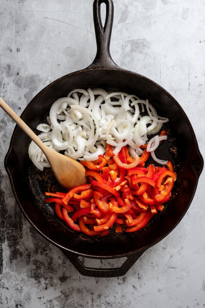Sautéing onions and bell peppers in a skillet.