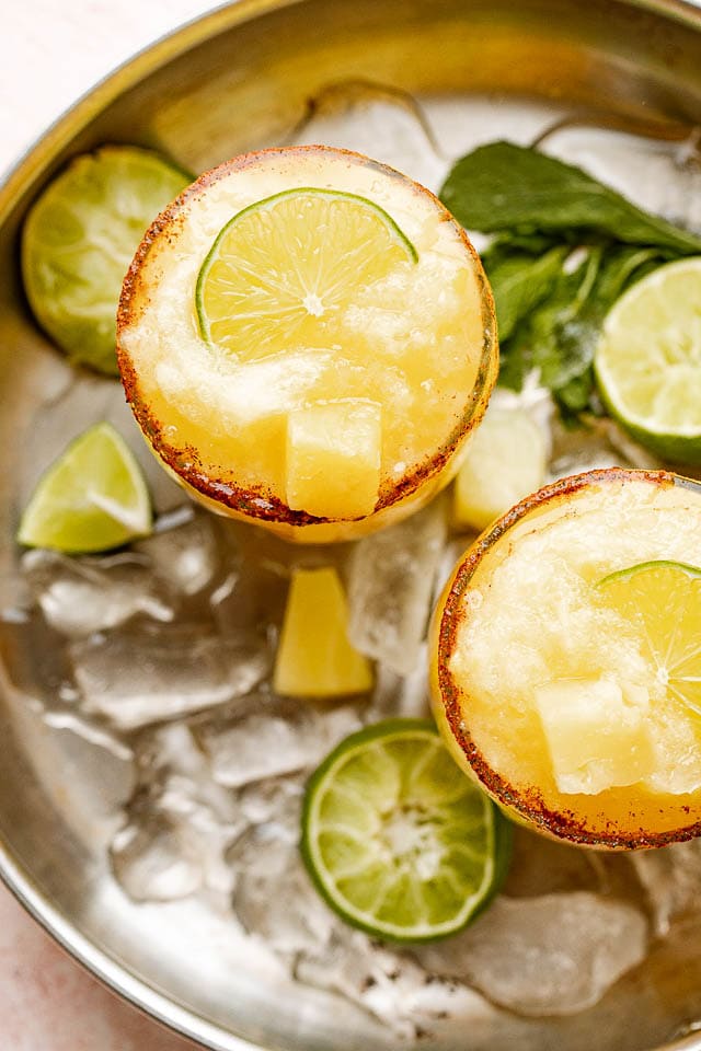 Overhead image of frozen pineapple margaritas garnished with lime.