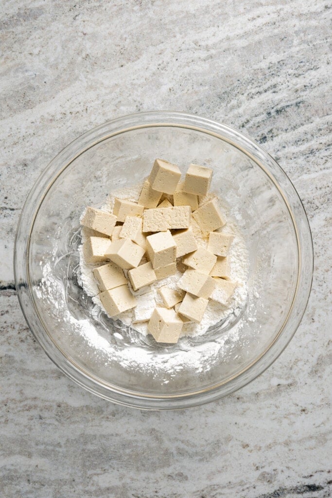 Coating cubes of tofu in cornstarch.
