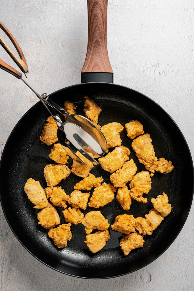 Browning breaded chicken pieces in a pan.